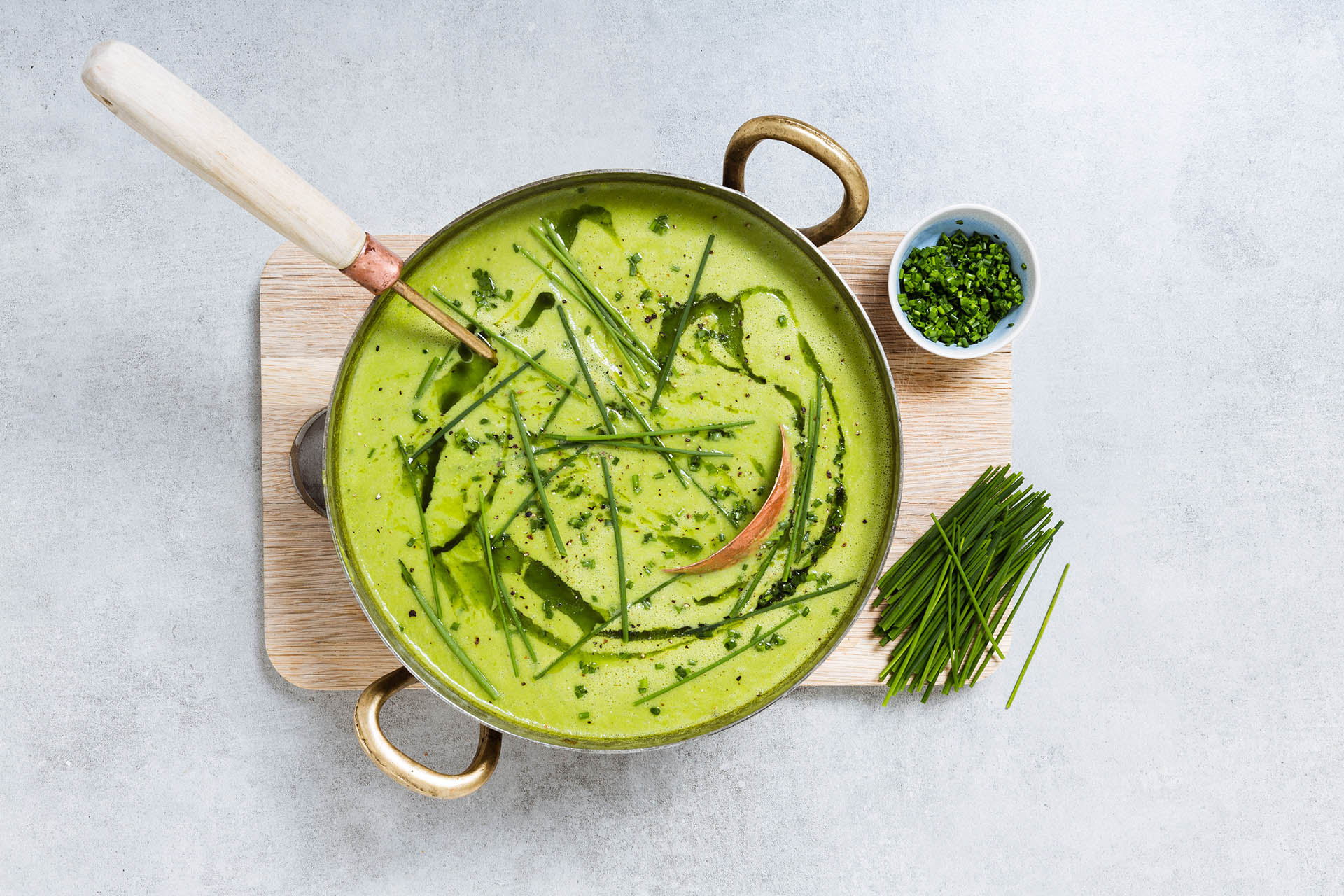green soup in a pot with long strands of chives