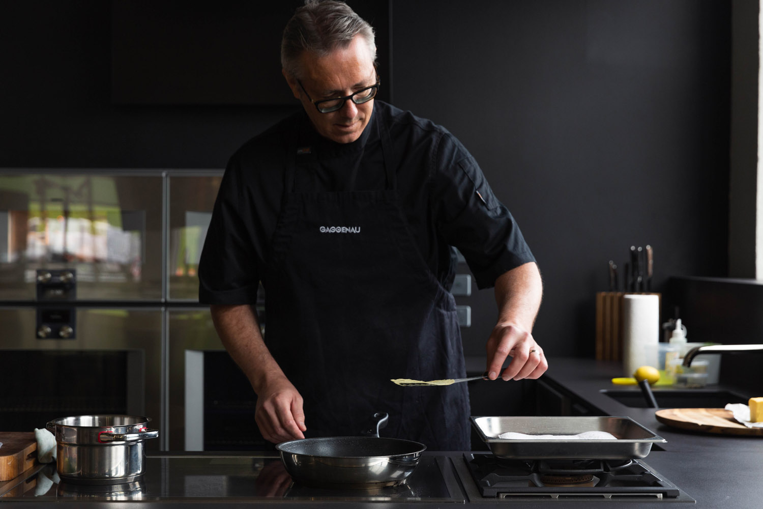 chef with black apron cooking on a pan